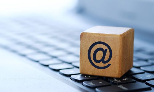 Internet symbol on a wooden cube on a computer keyboard, with a blurred background and a shallow depth of field.